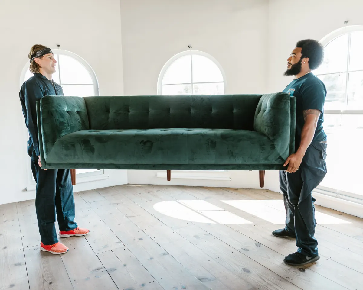 First Knock movers wrapping a sofa in a living room before a move